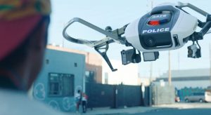 A police drone hovers in front of the face of a young man.