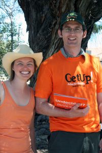 Me in a straw hat standing next to Dave wearing a cricket cap and orange GetUp shirt, holding the Undecided voter flyers. 